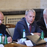 Osoby siedzące przy stole w sali konferencyjnej podczas spotkania