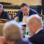 Osoby siedzące przy stole w sali konferencyjnej podczas spotkania