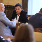 Osoby siedzące przy stole w sali konferencyjnej podczas spotkania