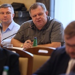 Osoby siedzące przy stole w sali konferencyjnej podczas spotkania